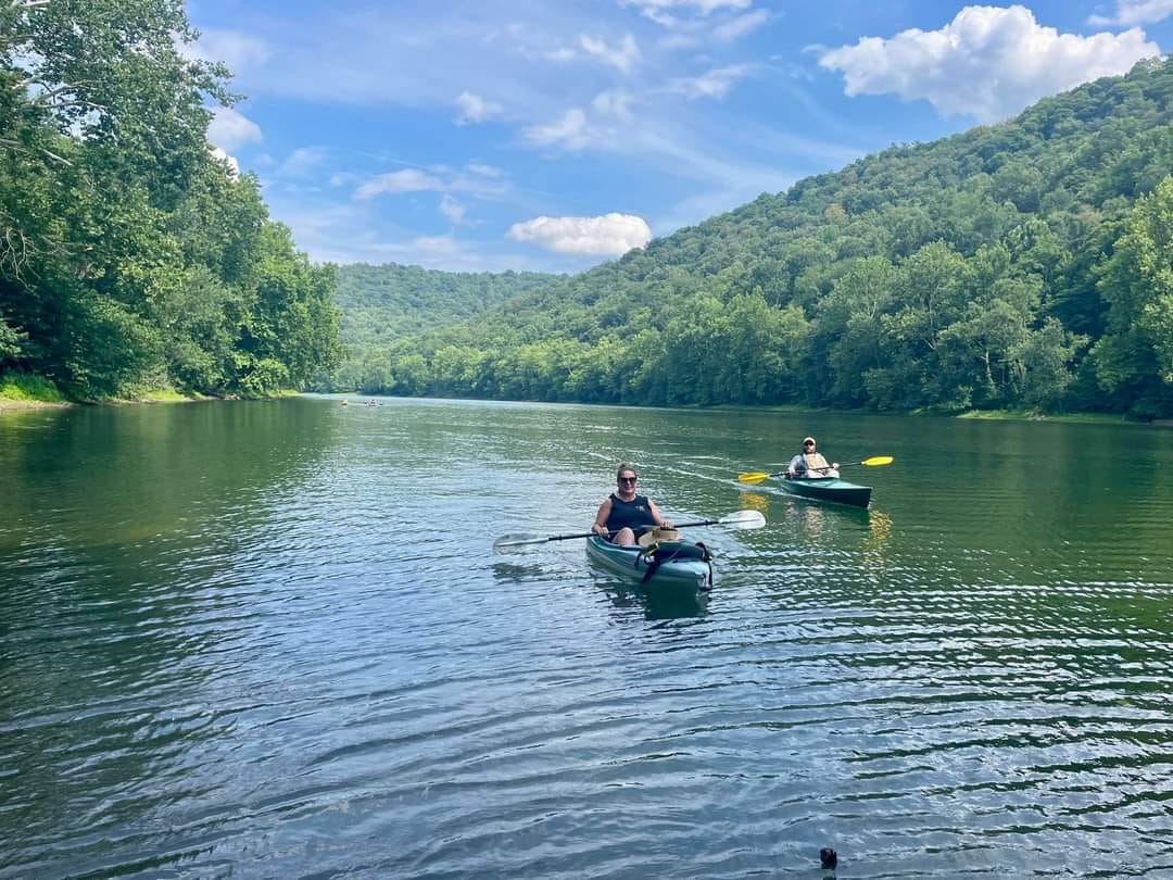 Two people in kayaks paddle down a river.