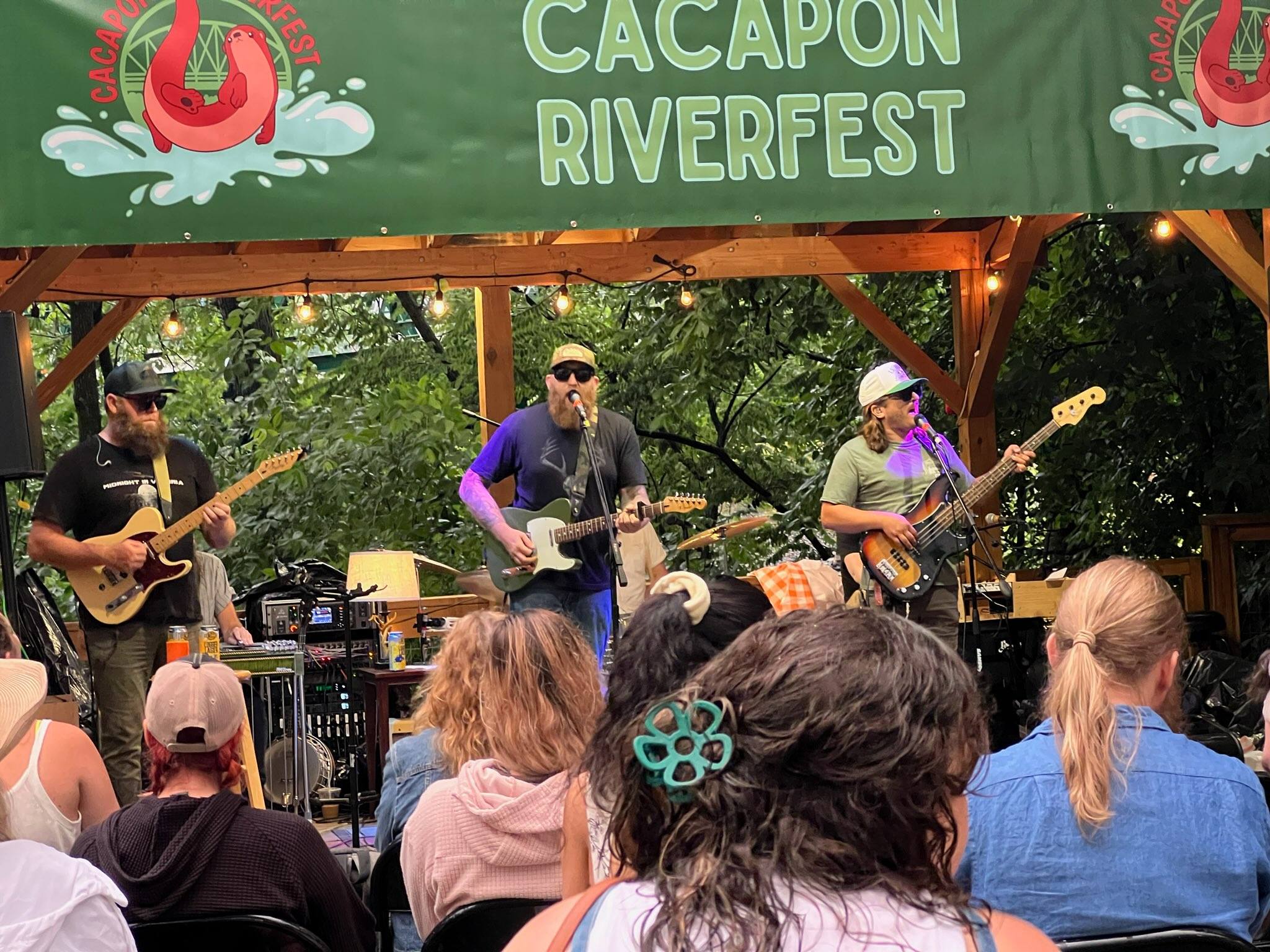 A band on a stage sings and plays instruments for a crowd.