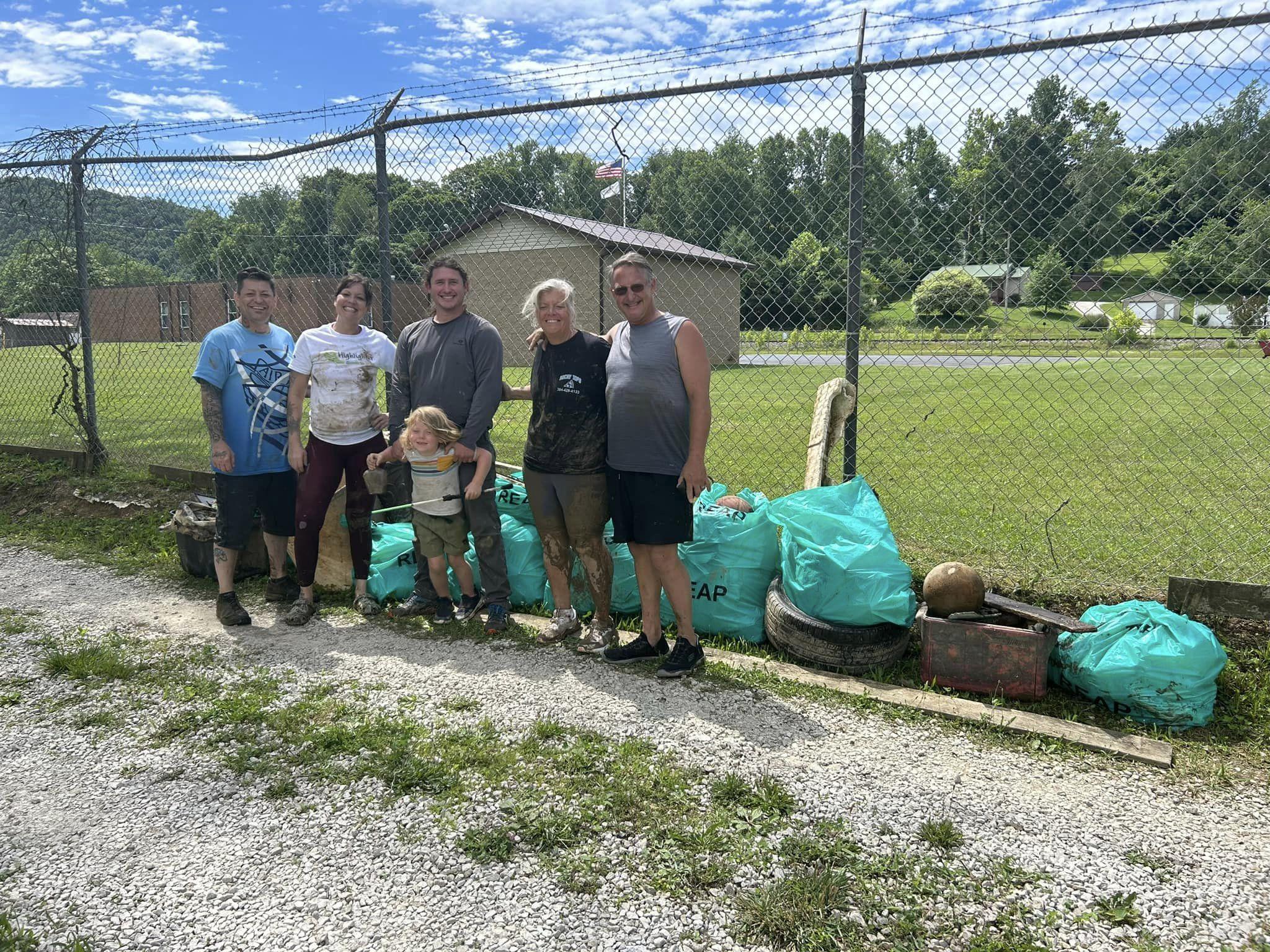 People stand in front of filled trash bags.